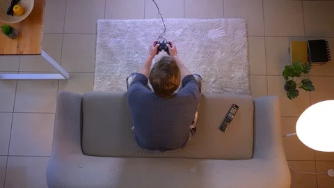 Closeup top shoot of young casually dressed male playing video games TV sitting Stock Footage 106945464