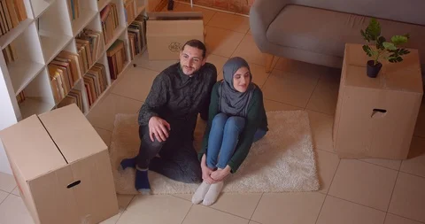 Closeup top shoot of young happy muslim couple sitting on the floor in a newly Video stock 106840664