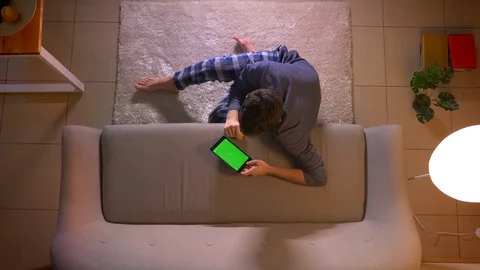 Closeup top shoot of young man watching an advertisement the tablet with green Video stock 106961538