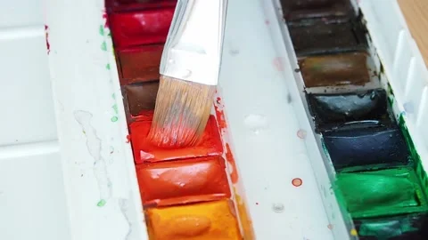 Closeup top view brush mixes water with orange watercolor paint Stock Footage 169753622