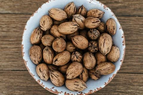 Closeup top view of pecan nuts in a white bowl on wooden table Stockfoto's