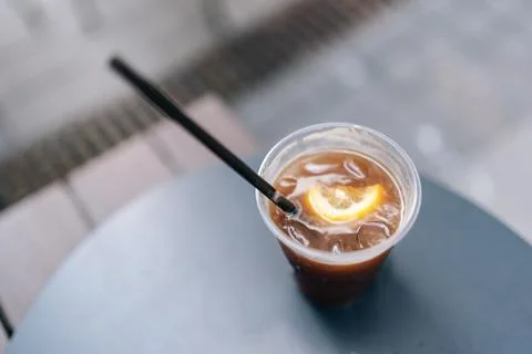 Closeup top view of plastic cup containing cold brew coffee with lemon slice and Stock Photos