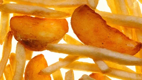Closeup top view of roasted potato chips and wedges rotating on white in 4K Vídeo Stock 87156751