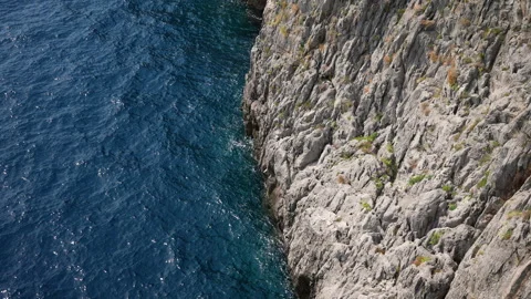 Closeup top view of sea waves crashing onto rocky shoreline of Amalfi Coast on Stock Footage 257613508
