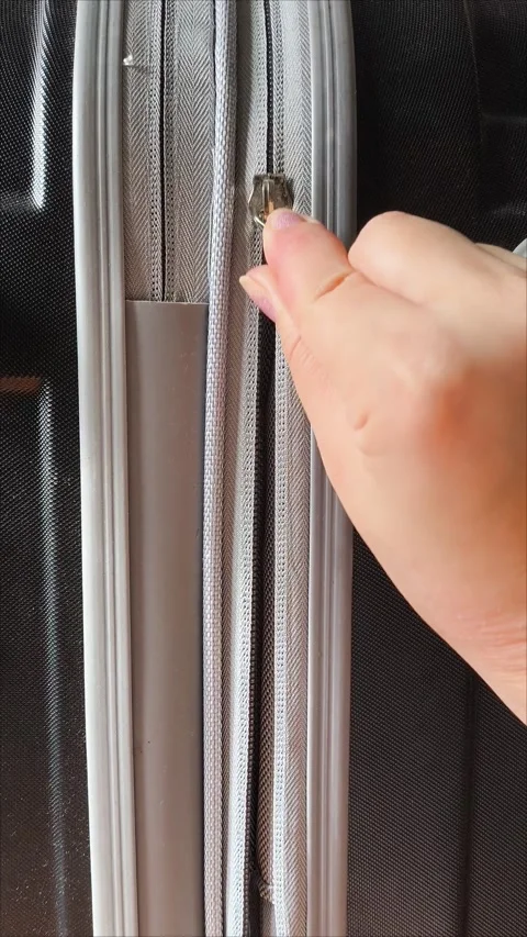 Closeup top view of silver zipper of hard shelled suitcase, new and clean Stock Footage 313833698