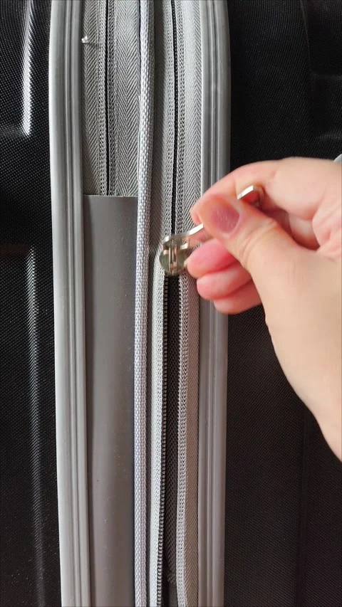 Closeup top view of silver zipper of hard shelled suitcase, new and clean Stock Footage 313833712