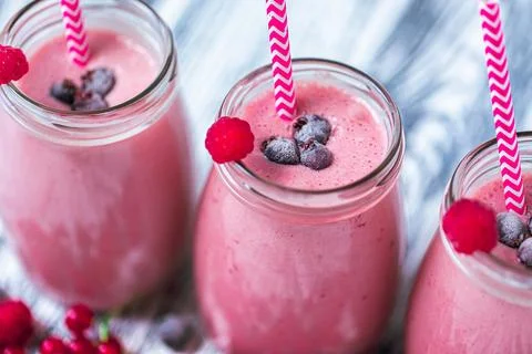 Closeup top view of three milkshakes in glasses jars made from raspberry Stock Photos