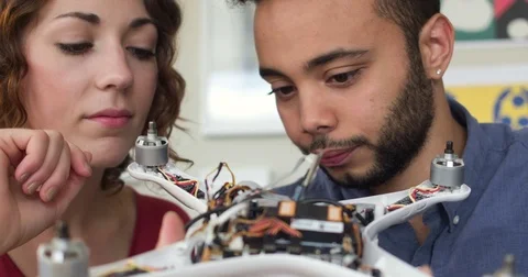Closeup Tracking Young Man and Woman Building A Robotic Quadcopter Drone Vidéo 82679442