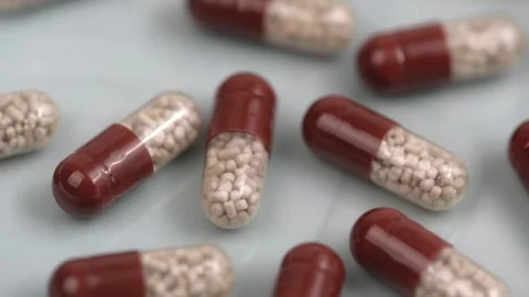 Closeup transparent capsules with a brown cap rotate on a gray background. Stock Footage 246918163
