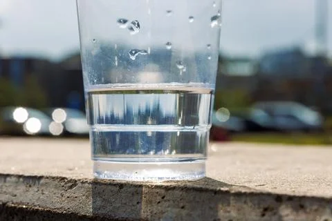 Closeup of a transparent disposable plastic cup partly filled with water on.. Stock Photos