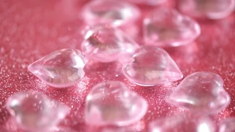 Closeup transparent pink hearts fall on shiny pink background, collide and spin. Stock Footage 263430760