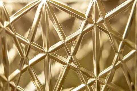 Closeup of the triangle-shaped patterns on the golden plastic surface Stock Photos