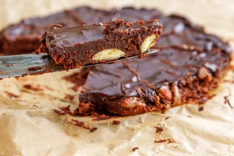 Closeup of a triangular slice of homemade chocolate almond brownie being li.. Stock Photos
