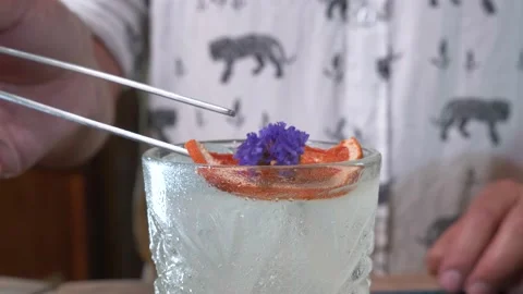 Closeup of tweezers adding orange and flower decoration to cocktail 4K 60fps Stock Footage 196821463