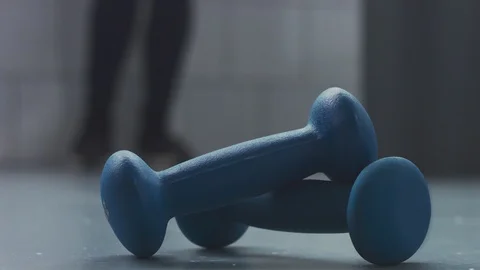 Closeup of two blue weights and woman from the blur zone came to take it Stock Footage 86975701