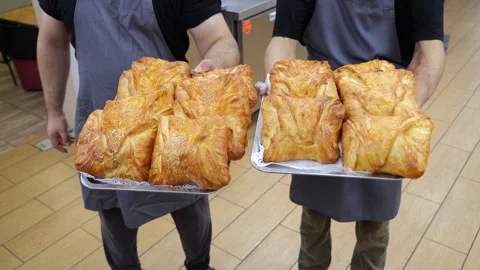 Closeup of two chefs holding a tray of fresh pastries in the restaurants kitchen Stock Footage 318139247