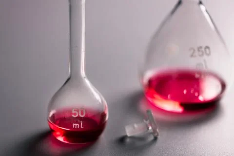 Closeup of two conical erlenmeyer flasks with red liquid and a glass plug. Stock Photos