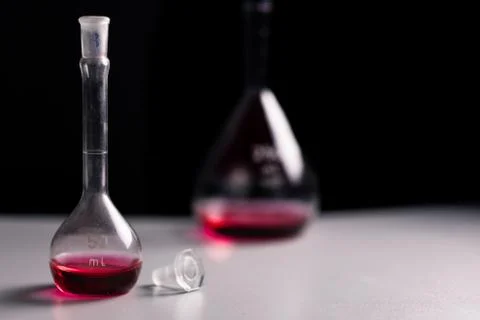 Closeup of two conical erlenmeyer flasks with red liquid and a glass plug. Stock Photos