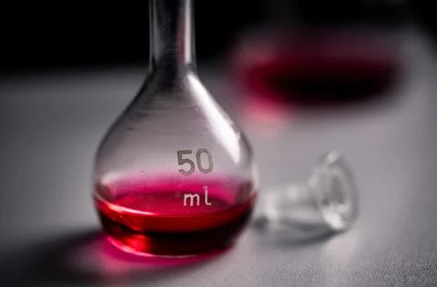Closeup of two conical erlenmeyer flasks with red liquid and a glass plug. Stock Photos