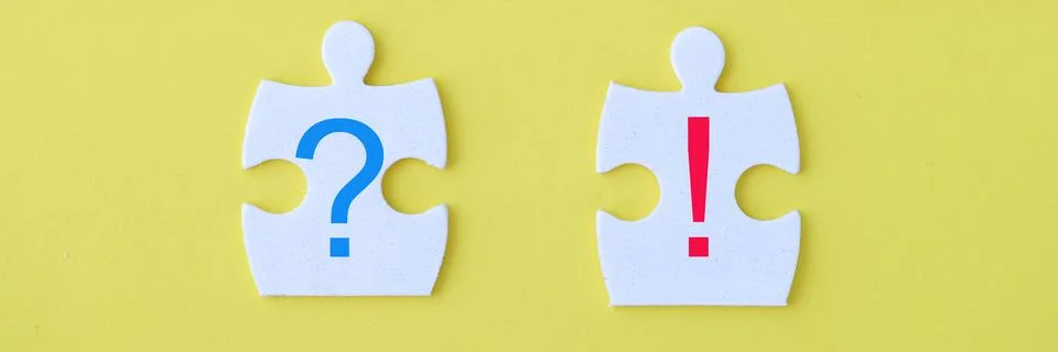 Closeup of two different pieces in front of white puzzle on yellow background Foto stock