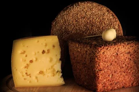 Closeup two farm rye bread and hard cheese piece Фото