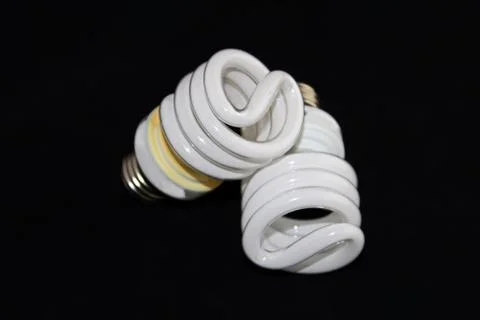 Closeup of two fluorescent light bulbs isolated on a black background Stock Photos