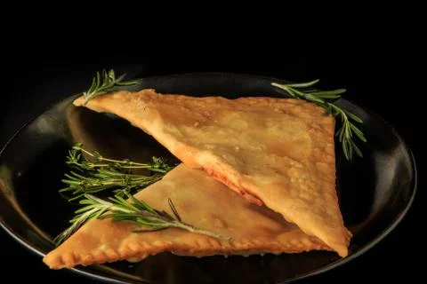 Closeup two fried triangles of caucasian chebureki with green rosemary Stock Photos