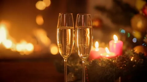 Closeup of two glasses of fizzy champagne in front of burning fireplace. Deco Stock Footage