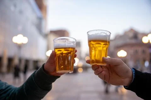 Closeup of two hands clinking beer stein glasses. Stock Photos