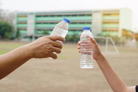Closeup two hands hold two drinking water bottles outdoor. Foto stock