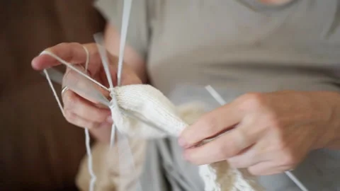 A closeup of two hands skillfully knitting with multiple colorful needles and Stock Footage 314988060