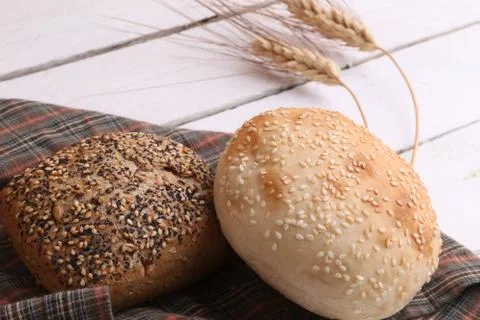 Closeup of two loaves of bread on a patterned cloth on a white wooden surface 写真素材