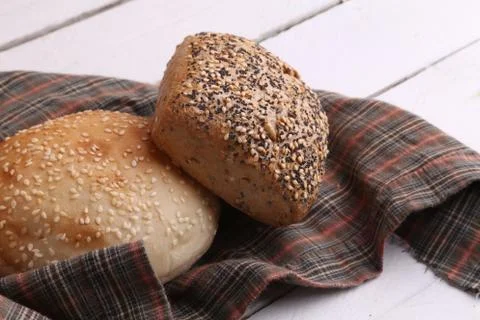 Closeup of two loaves of bread on a patterned cloth on a white wooden surface 写真素材