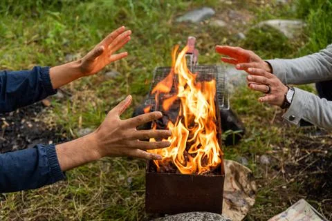Closeup of two men warming hands by the fire Stock Photos