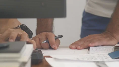 Closeup of two men working on a desk with computer and over a paper project Stock Footage 118004417