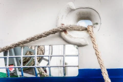 Closeup on two tightropes going through ships side hole from anchor to anchor Stock Photos