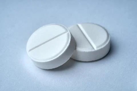 Closeup of two white tablets on a white background with texture. Stock Photos