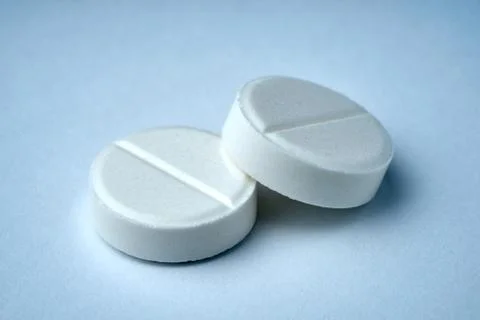 Closeup of two white tablets on a white background with texture. Stock Photos