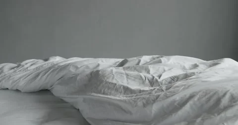 Closeup on unmade bed with cotton bedsheet and soft blanket Stock Footage 256662724