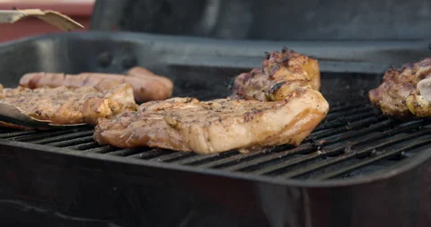 Closeup of unrecognizable man grilling some meat in a backyard Stock Footage 131424877