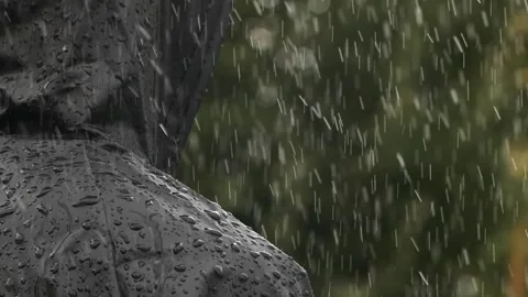 Closeup unrecognizable person in heavy rain, young man in water proof black coat 動画素材 254053091