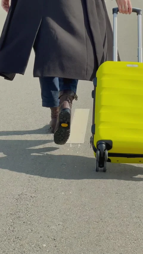 Closeup of unrecognizable womans feet, walking with yellow suitcase Stock Footage 313733636