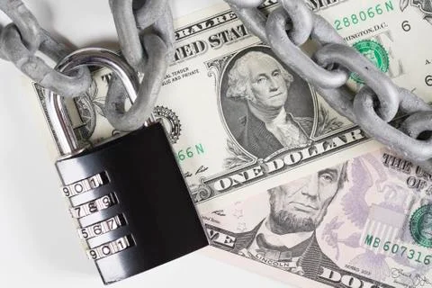Closeup of US Dollar banknotes under metallic chain and combination padlock Stock Photos