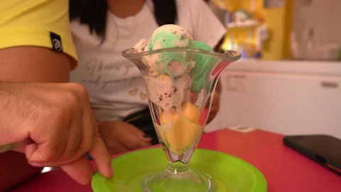 Closeup of various green, yellow, red and white ice cream balls in a glass cup a Vidéo 196728496