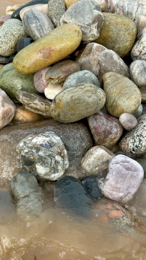 Closeup of variously colored smooth stones on a beach with water flowing ov.. Stock Footage 338414327
