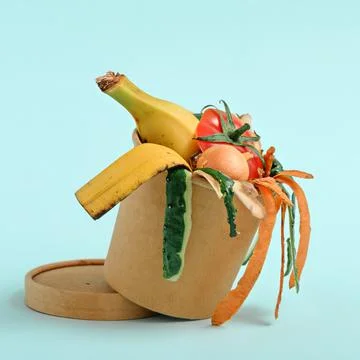 Closeup vegetable peels in compost bin on blue background, compost concept. Stock Photos