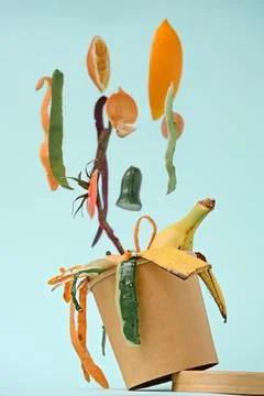 Closeup vegetable peels in compost bin with levitation effect on blue backgro Stock Photos