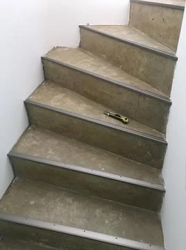 A closeup vertical shot of a cutter tool on a concrete spiral staircase durin 스톡 사진