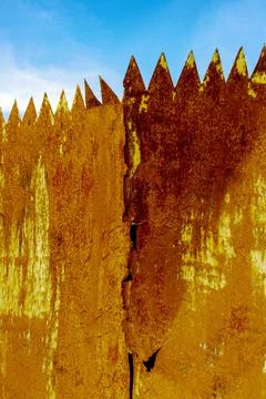 Closeup vertical shot of rusty weathered spiked fence with cracks under an Stock Photos