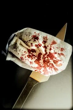 A closeup vertical shot of a sharp knife and a blood-stained face mask - the  Stock Photos